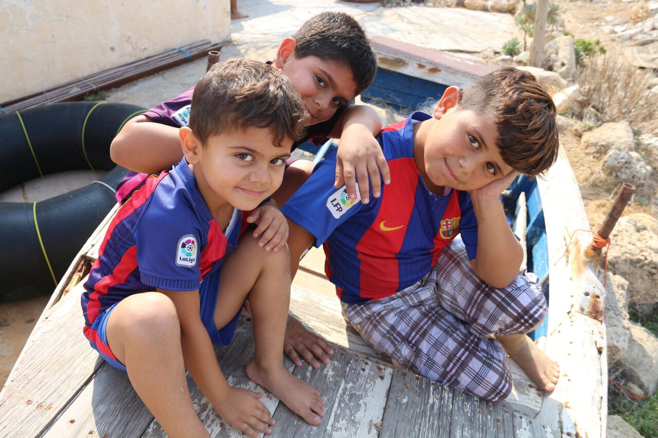 شبابيك أطفال يلهون على قارب صيد على شاطىء تجمع "جل البحر